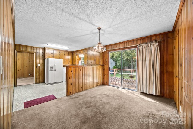 331 Elwood St, Kannapolis, NC 28081 - kitchen featuring white fridge with ice dispenser, wood walls, light colored carpet, brown cabinets, and a textured ceiling
