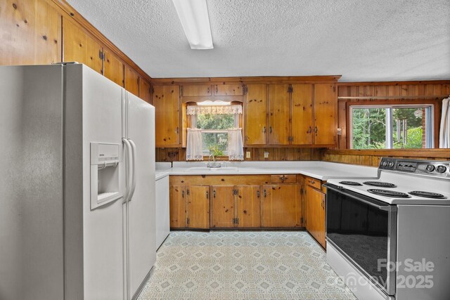 331 Elwood St, Kannapolis, NC 28081 - kitchen featuring white appliances, healthy amount of natural light, a textured ceiling, light countertops, and brown cabinetry