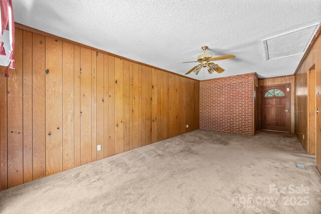 331 Elwood St, Kannapolis, NC 28081 - spare room with carpet, wooden walls, a textured ceiling, attic access, and a ceiling fan