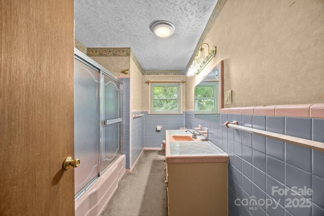 331 Elwood St, Kannapolis, NC 28081 - full bathroom featuring vanity, a textured ceiling, wainscoting, and shower / bath combination with glass door