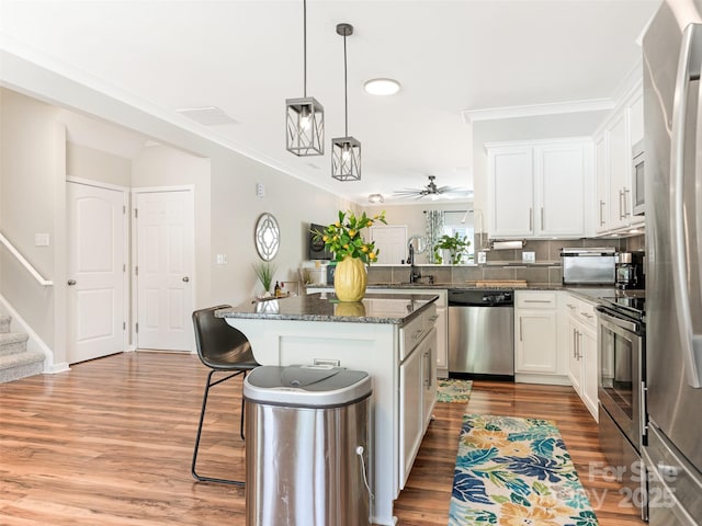 342 Battery Cir, Clover, SC 29710 - kitchen featuring appliances with stainless steel finishes, a kitchen breakfast bar, light wood-type flooring, white cabinetry, and crown molding