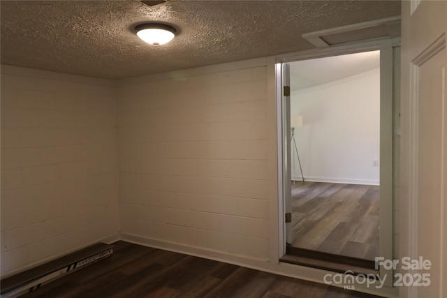 127 Setzer St, Spindale, NC 28160 - spare room featuring dark wood-type flooring, concrete block wall, a textured ceiling, and attic access