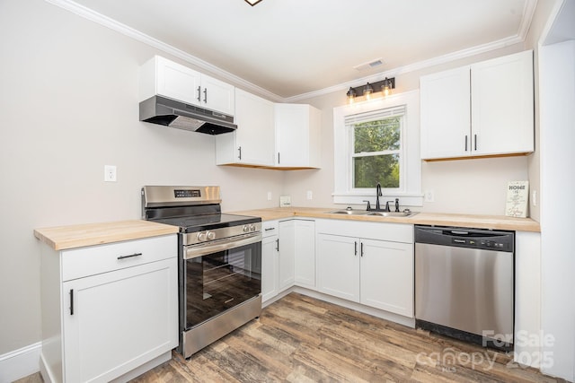 900 N Salisbury Ave, Spencer, NC 28159 - kitchen with stainless steel appliances, under cabinet range hood, light wood finished floors, ornamental molding, and white cabinetry