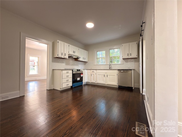 179 Duval St NW, Concord, NC 28025 - kitchen featuring appliances with stainless steel finishes, under cabinet range hood, dark wood finished floors, tasteful backsplash, and white cabinets