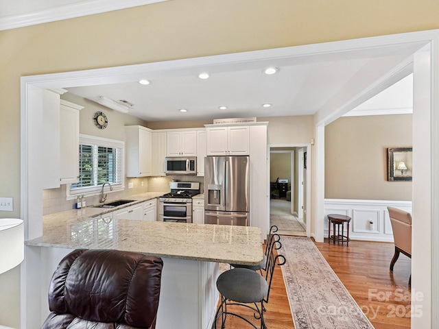 1842 Caroline Way, Fort Mill, SC 29715 - kitchen with appliances with stainless steel finishes, a peninsula, a breakfast bar, light wood-style flooring, and light stone countertops