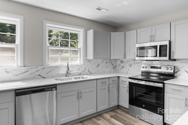 509 8th Avenue Ext, Cramerton, NC 28032 - kitchen featuring appliances with stainless steel finishes, gray cabinets, light countertops, backsplash, and light wood-style flooring