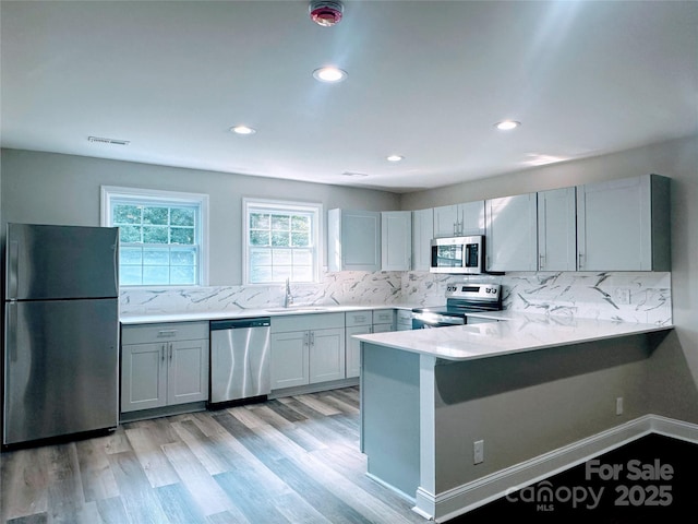 509 8th Avenue Ext, Cramerton, NC 28032 - kitchen featuring appliances with stainless steel finishes, decorative backsplash, a peninsula, light wood-style flooring, and recessed lighting