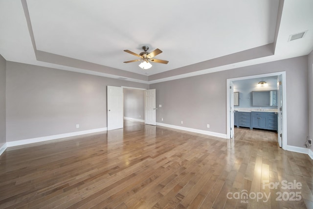 329 Wave Crest Dr, Tega Cay, SC 29708 - unfurnished bedroom featuring a tray ceiling, wood finished floors, connected bathroom, and ceiling fan