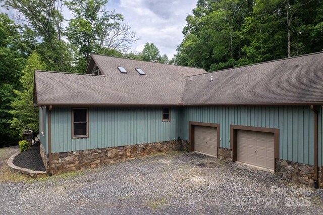 486 Center Dr Unit 7B, Bryson City, NC 28713 - view of front of property with a garage, roof with shingles, gravel driveway, and stone siding