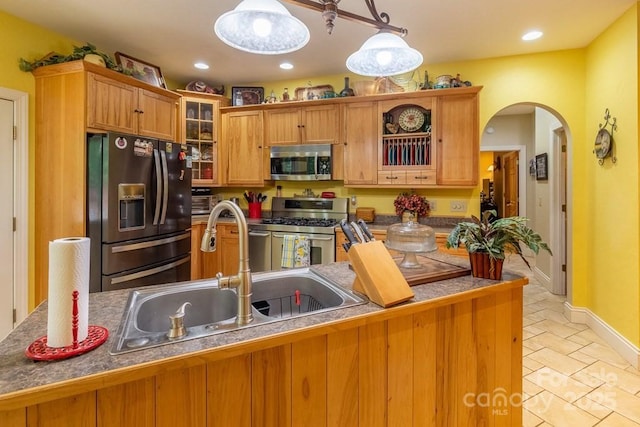 486 Center Dr Unit 7B, Bryson City, NC 28713 - kitchen with appliances with stainless steel finishes, arched walkways, glass insert cabinets, hanging light fixtures, and brown cabinets
