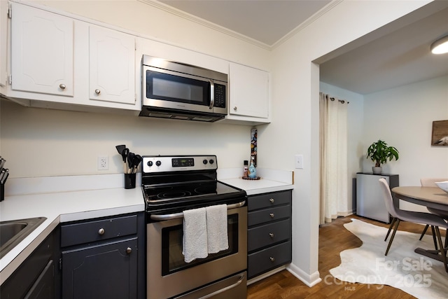 2620 Park Rd Unit F, Charlotte, NC 28209 - kitchen with appliances with stainless steel finishes, white cabinetry, crown molding, dark wood-style flooring, and light countertops