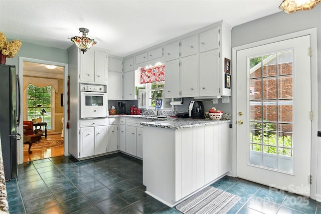 701 4th Ave NE, Conover, NC 28613 - kitchen featuring white oven, freestanding refrigerator, a peninsula, and white cabinets