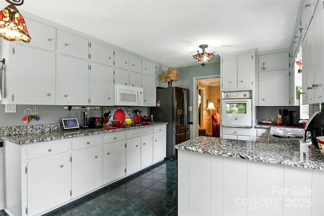 701 4th Ave NE, Conover, NC 28613 - kitchen featuring white appliances, white cabinets, a peninsula, dark tile patterned flooring, and tasteful backsplash