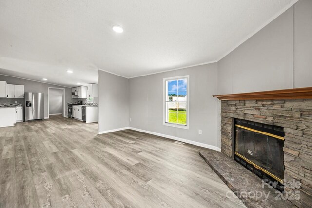 1133 Lynn Ln, Catawba, NC 28609 - unfurnished living room with a stone fireplace, light wood-type flooring, ornamental molding, recessed lighting, and vaulted ceiling