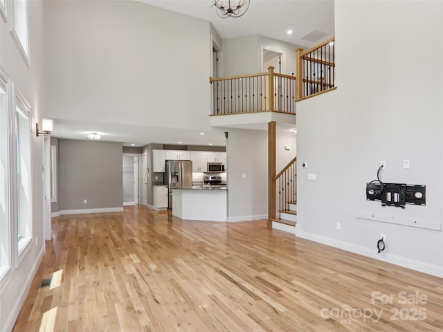 278 Ollie Weaver Rd, Weaverville, NC 28787 - unfurnished living room featuring a high ceiling, stairs, light wood-style flooring, and plenty of natural light