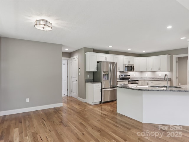 278 Ollie Weaver Rd, Weaverville, NC 28787 - kitchen featuring appliances with stainless steel finishes, dark stone countertops, white cabinets, light wood-type flooring, and recessed lighting