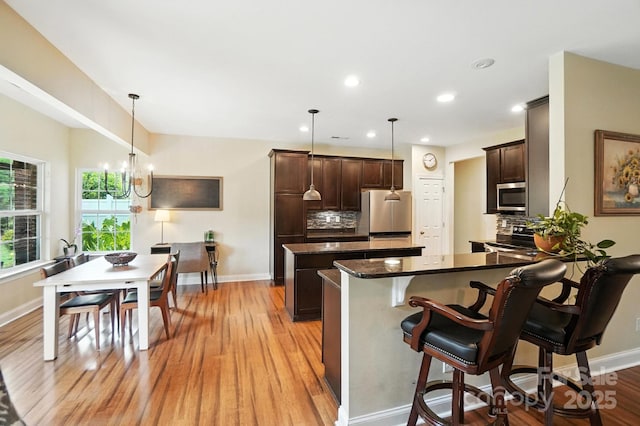 1006 Spring Rose Ln, Matthews, NC 28104 - kitchen with appliances with stainless steel finishes, light wood-style flooring, dark brown cabinets, a kitchen island, and recessed lighting