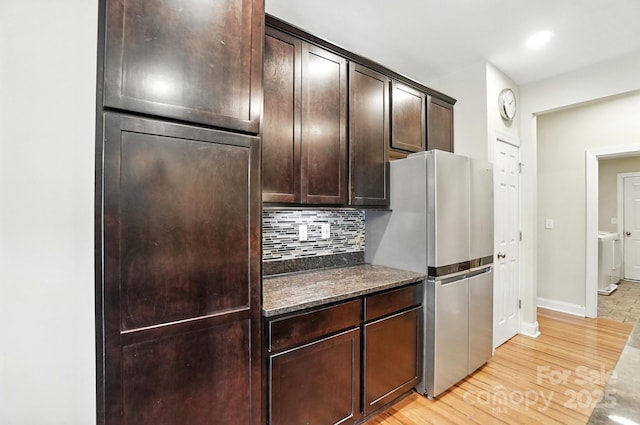 1006 Spring Rose Ln, Matthews, NC 28104 - kitchen with backsplash, dark brown cabinets, freestanding refrigerator, light wood-type flooring, and washer / clothes dryer