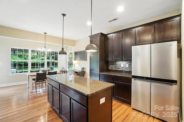 1006 Spring Rose Ln, Matthews, NC 28104 - kitchen featuring freestanding refrigerator, a kitchen island, dark stone countertops, backsplash, and light wood-style flooring