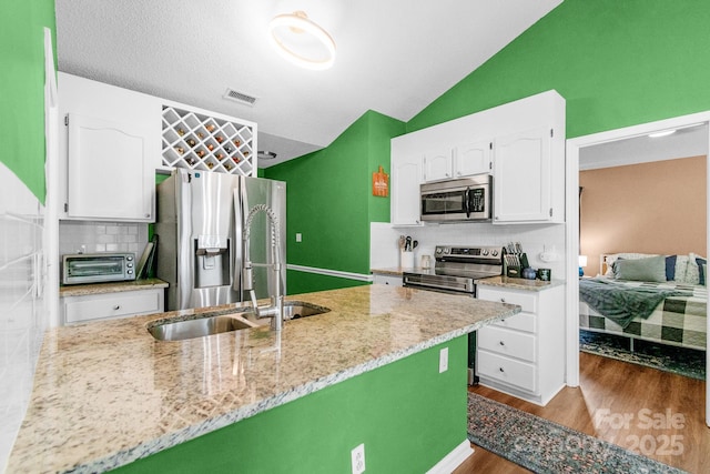 4614 Jacquelyne Dr, Indian Trail, NC 28079 - kitchen featuring stainless steel appliances, white cabinetry, vaulted ceiling, tasteful backsplash, and dark wood-style flooring