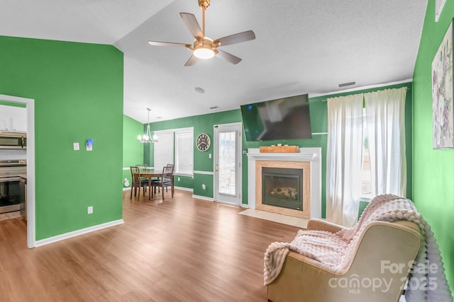 4614 Jacquelyne Dr, Indian Trail, NC 28079 - living room featuring lofted ceiling, wood finished floors, a fireplace with flush hearth, a ceiling fan, and a chandelier