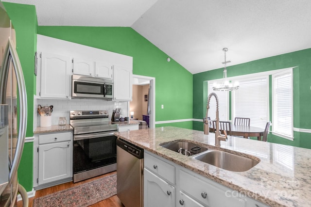 4614 Jacquelyne Dr, Indian Trail, NC 28079 - kitchen with appliances with stainless steel finishes, vaulted ceiling, white cabinetry, light wood-type flooring, and a chandelier
