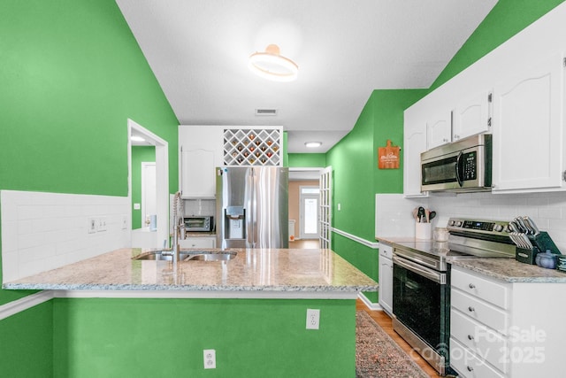 4614 Jacquelyne Dr, Indian Trail, NC 28079 - kitchen featuring appliances with stainless steel finishes, white cabinetry, tasteful backsplash, and a peninsula