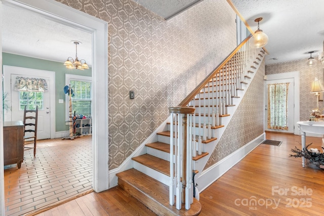313 E Main St, Morganton, NC 28655 - stairway featuring wallpapered walls, a chandelier, hardwood / wood-style flooring, and a textured ceiling