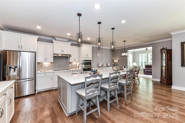 5129 Devonshire Rd, Denver, NC 28037 - kitchen featuring appliances with stainless steel finishes, a breakfast bar area, light countertops, white cabinetry, and crown molding
