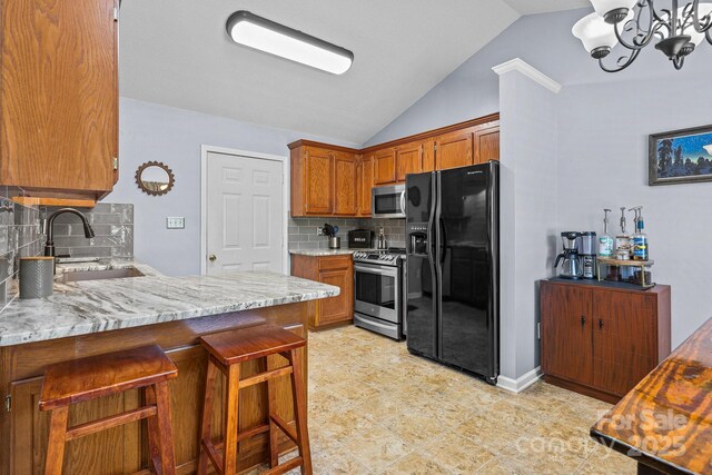 2906 Plantation Way, Albemarle, NC 28001 - kitchen with stainless steel appliances, lofted ceiling, brown cabinets, tasteful backsplash, and a chandelier