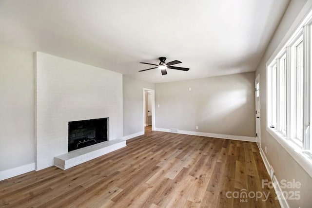 7724 E Holly Grove Rd, Thomasville, NC 27360 - unfurnished living room with light wood-style floors, a ceiling fan, and a brick fireplace