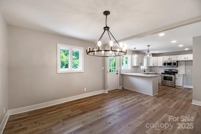7724 E Holly Grove Rd, Thomasville, NC 27360 - kitchen with stainless steel appliances, a chandelier, a peninsula, white cabinets, and plenty of natural light