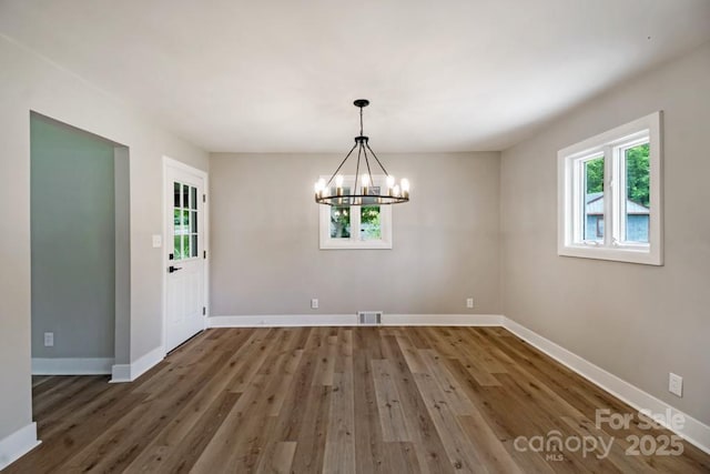 7724 E Holly Grove Rd, Thomasville, NC 27360 - unfurnished dining area featuring healthy amount of natural light, wood finished floors, and a chandelier