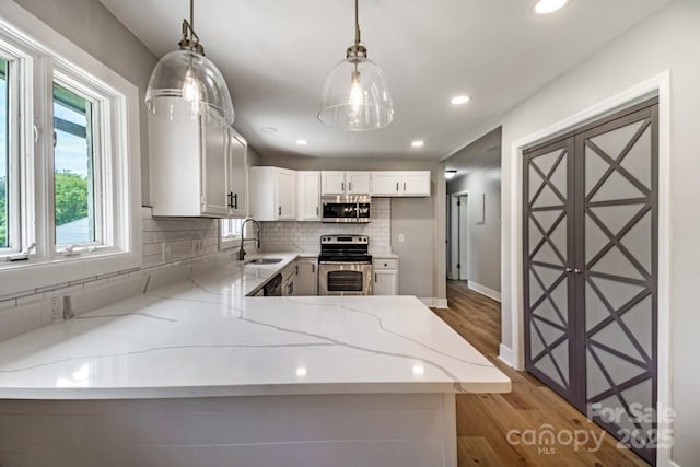 7724 E Holly Grove Rd, Thomasville, NC 27360 - kitchen featuring stainless steel appliances, light stone countertops, light wood-style flooring, decorative backsplash, and a peninsula