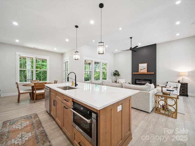 2108 Lakeview Cir, Matthews, NC 28105 - kitchen with light wood-type flooring, recessed lighting, a glass covered fireplace, plenty of natural light, and a kitchen island with sink