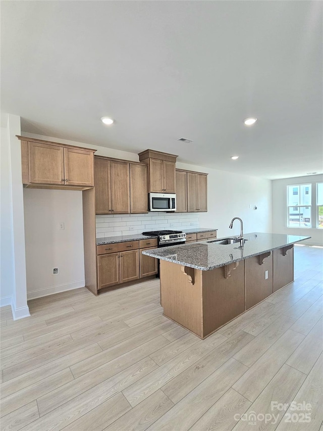 2137 Barrowcliffe Dr Unit 49, Concord, NC 28027 - kitchen featuring stainless steel microwave, light wood finished floors, stone counters, a kitchen bar, and a kitchen island with sink