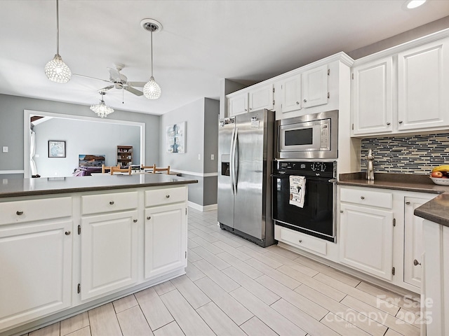 14019 Fountain Ln, Charlotte, NC 28278 - kitchen with stainless steel appliances, dark countertops, backsplash, white cabinets, and decorative light fixtures
