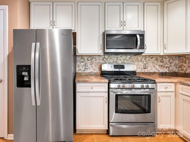 621 E Park Pl, Hendersonville, NC 28791 - kitchen featuring appliances with stainless steel finishes, backsplash, light stone counters, and light wood-style flooring