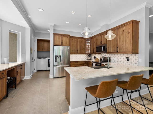 102 Gap Creek Rd, Fletcher, NC 28732 - kitchen with appliances with stainless steel finishes, independent washer and dryer, a peninsula, tasteful backsplash, and brown cabinetry