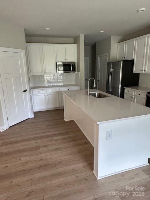 1411 Cottage Green Dr Unit 218, Monroe, NC 28112 - kitchen with stainless steel microwave, refrigerator with ice dispenser, white cabinets, light wood-style floors, and light countertops