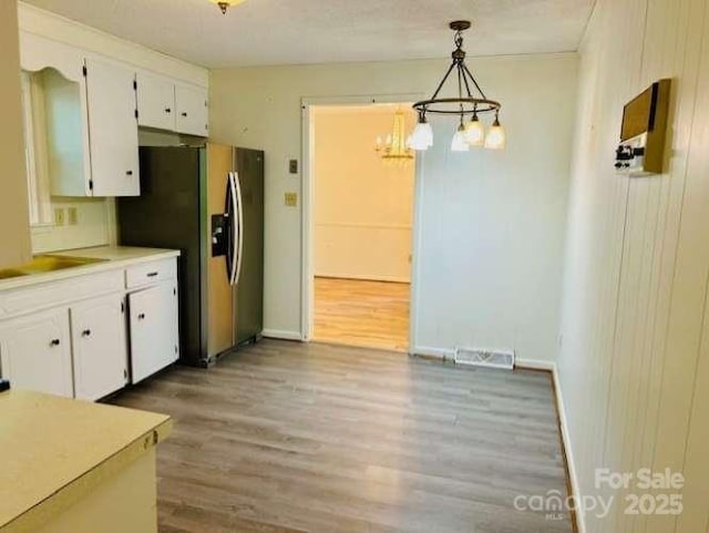 2660 Tiffany St, Conover, NC 28613 - kitchen featuring stainless steel fridge, light wood finished floors, a chandelier, white cabinets, and light countertops