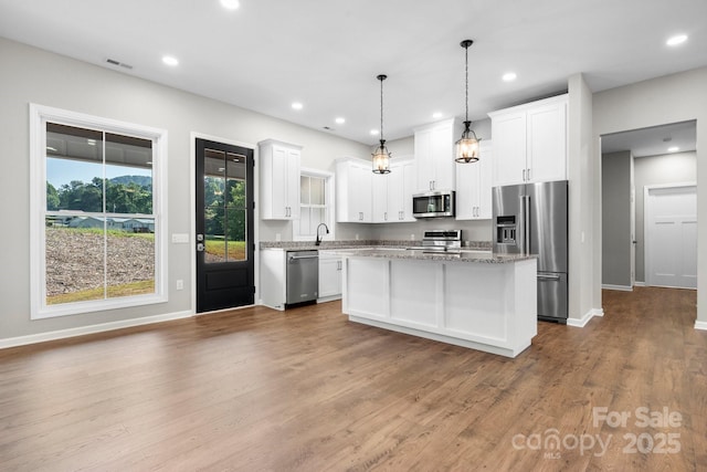 3981 Zero Mull Rd, Morganton, NC 28655 - kitchen with stainless steel appliances, a center island, white cabinetry, wood finished floors, and decorative light fixtures