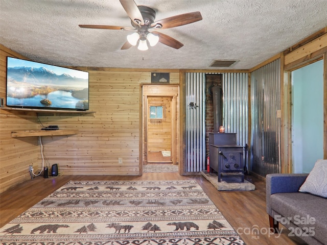 32 Saunooke Rd, Asheville, NC 28805 - living room featuring wood walls, a wood stove, a ceiling fan, wood finished floors, and a textured ceiling