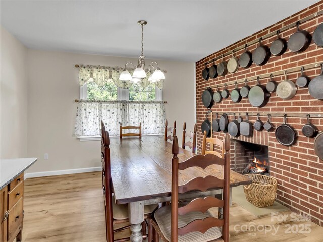 463 Golf Course Rd, Clyde, NC 28721 - dining room featuring wood finished floors, a chandelier, a fireplace, and brick wall