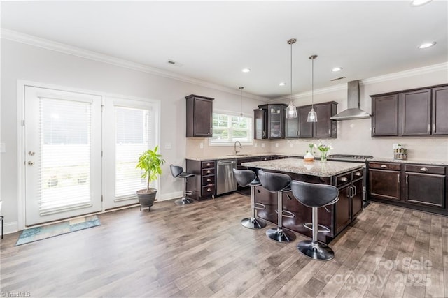 2110 Owls View Ln, Colfax, NC 27235 - kitchen with wall chimney range hood, stainless steel appliances, light wood-style floors, dark brown cabinetry, and crown molding
