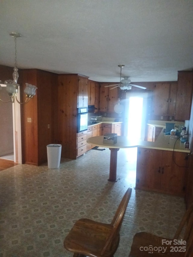 2815 Highland Dr, Lincolnton, NC 28092 - kitchen with brown cabinetry, a ceiling fan, a chandelier, hanging light fixtures, and oven