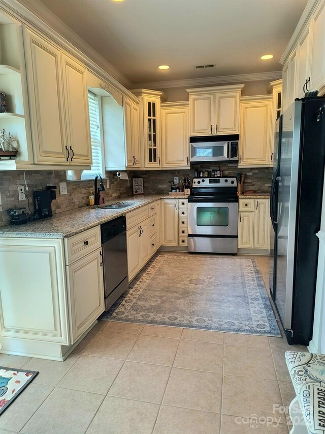 10825 Traders Ct, Davidson, NC 28036 - kitchen featuring stainless steel appliances, cream cabinetry, backsplash, light stone countertops, and crown molding
