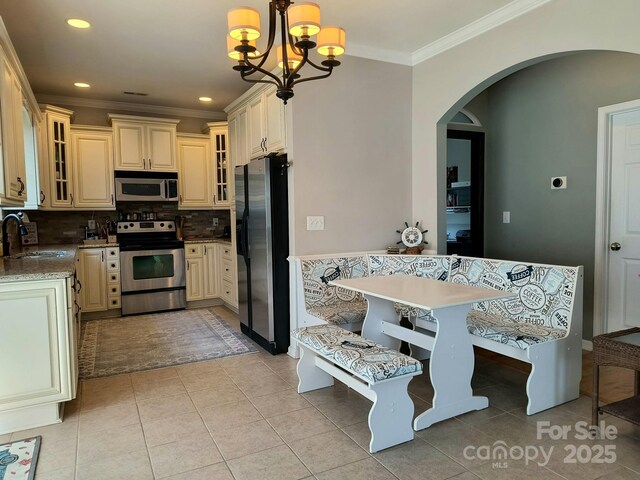 10825 Traders Ct, Davidson, NC 28036 - kitchen with appliances with stainless steel finishes, arched walkways, ornamental molding, decorative backsplash, and light tile patterned floors