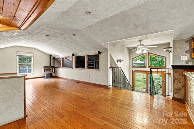 3724 County Home Rd, Conover, NC 28613 - unfurnished living room with vaulted ceiling, hardwood / wood-style floors, ceiling fan, and a wood stove
