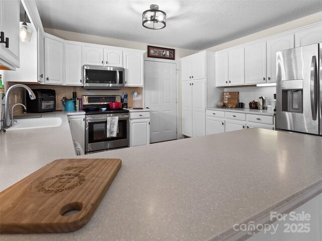 3906 Brickfield St, Hickory, NC 28602 - kitchen with stainless steel appliances, backsplash, white cabinets, and a textured ceiling